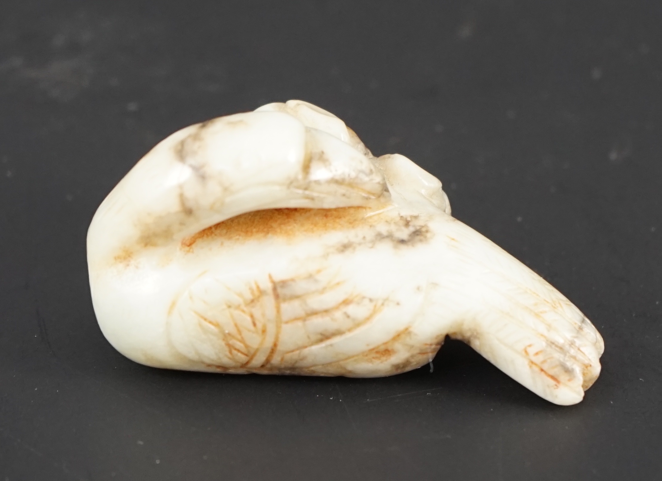 A Chinese white and black jade figure of a preening duck, Ming dynasty, 5.8 cm long